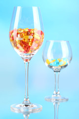 Goblets with pills on blue background