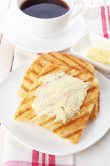Grilled bread with butter and cup of coffee on wooden table