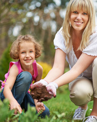 Mutter und Tochter pflanzen Blumen im Garten