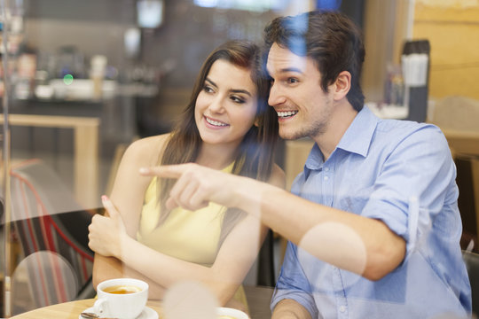 Curious Couple Looking Away Through Window In Cafe