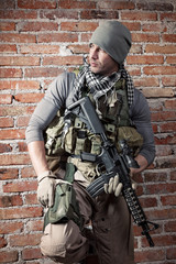 Portrait fo soldier with rifle on bricks background