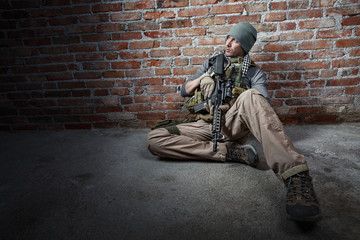Soldier with rifle on bricks background