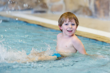 Fototapeta na wymiar Activities on the pool, toddler boy swimming, having fun and pla