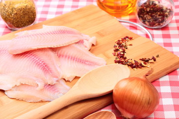 Raw fish tilapia on cutting board and spices