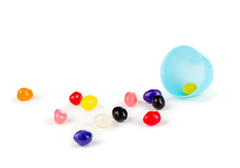 Colorful jelly beans spilled out of a plastic Easter egg.