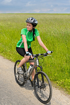 Woman biking on countryside road sunny day