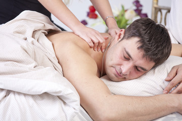 Man receiving massage on bed