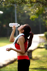 Slim young woman drinking water after exercises