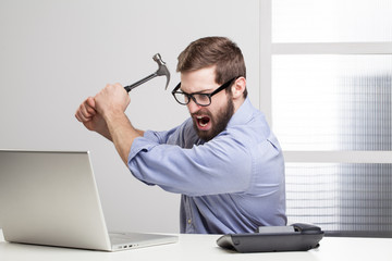 Furious businessman destroying his laptop with a hammer.. - 61585881