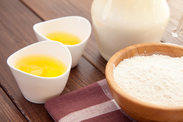 Eggs, milk and flour on a wooden table