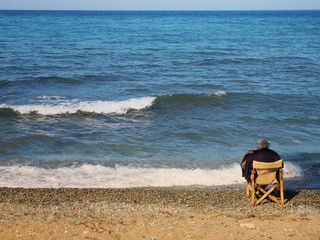 Fototapeta na wymiar Starzec na wybrzeże siedzi na krześle