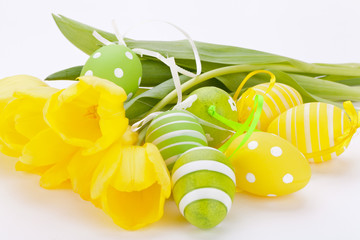 Farbenfrohe gelbe Tulpen mit grünen Blättern und Ostereiern zu