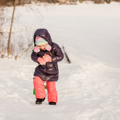 Fototapeta na wymiar Little girl pulls a sled in warm winter day