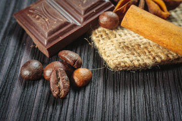 Chocolate bar and spices on wooden table