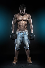 Fototapeta na wymiar Muscular bodybuilder guy doing exercises with dumbbells over bla