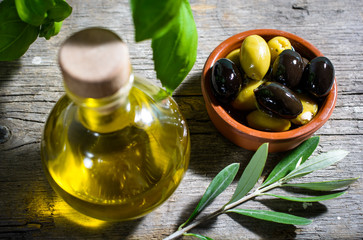 Olivenöl und Oliven serviert auf rustikalem Holztisch