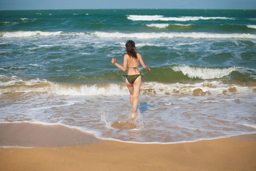 Fototapeta premium Young woman running to swim in ocean