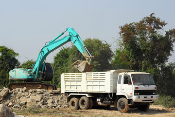 excavator loading stone dump truck on construction site