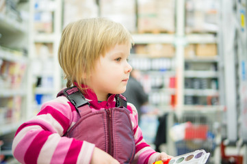 Adorable girl sit on shopping cart  in supermarket