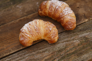 Two croissants on wooden planks