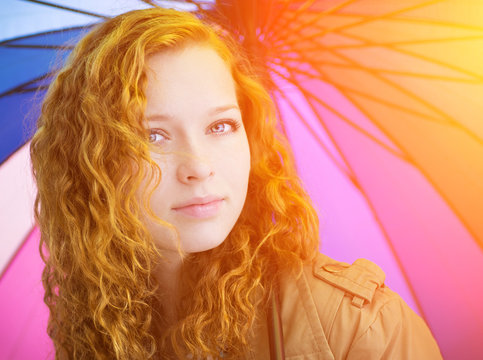 Redhead girl and colorful umbrella as background.