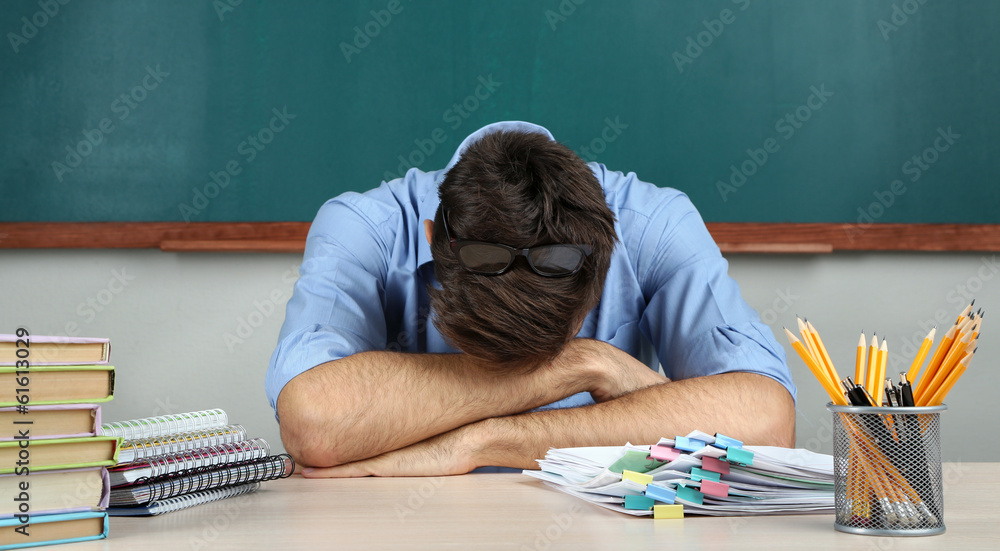 Wall mural young teacher sitting in school classroom