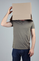 Man with cardboard box on his head on grey background