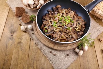 Delicious fried mushrooms in pan on table close-up