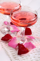 Composition with pink sparkle wine in glasses and rose petals