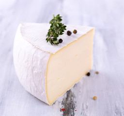 Tasty Camembert cheese with spices, on wooden table