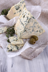 Fototapeta na wymiar Tasty blue cheese with thyme and olives on paper