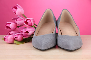 Obraz na płótnie Canvas Beautiful grey female shoes and flowers on pink background