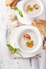 Mushroom soup in white pots, on napkin, on wooden background