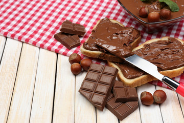 Bread with sweet chocolate hazelnut spread on wooden background