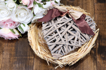 Decorative heart in nest, on color wooden background