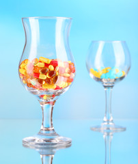Goblets with pills on blue background