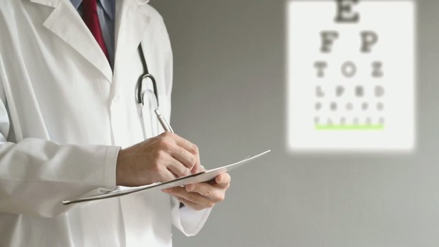 Male ophthalmologist doctor writing prescription to patient afte