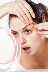 Obraz na płótnie Canvas woman remove hair from her eyebrows using tweezers