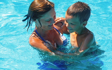 Mother train her son to swim in the pool.