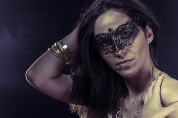 Beautiful young woman in mysterious black Venetian mask. Fashion