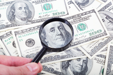 Money american hundred dollar bills and magnifying glass.