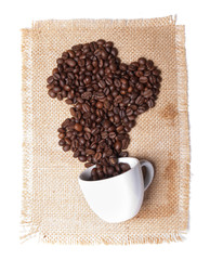 white cup with coffee beans on burlap background.