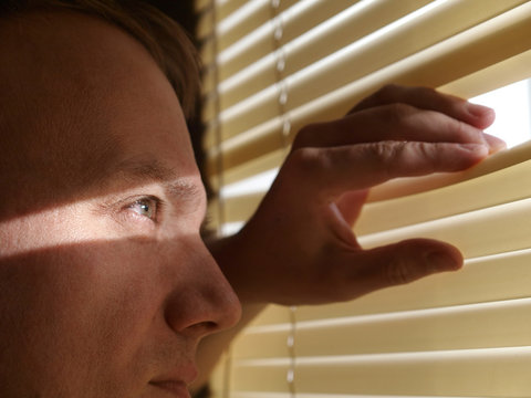 Man Looking Through Blinds