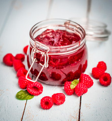 Raspberry jam in a jar on wooden background