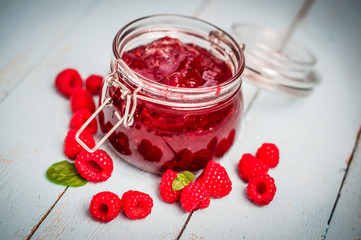 Raspberry jam in a jar on wooden background