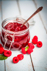 Raspberry jam in a jar on wooden background