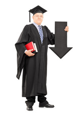 Mature man in graduation gown holding big arrow pointing down
