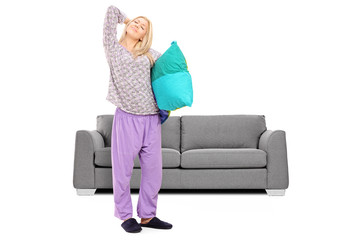 Young woman in pajamas stretching in front of a sofa