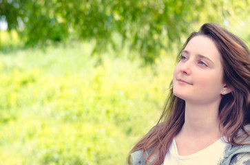 Naklejka premium Beautiful young woman daydreaming in a park