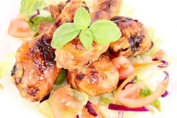 Fried chicken legs with side salad decorated with basil